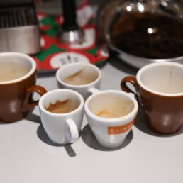 Mehrere leere Espresso‑ und Kaffee-Tassen mit Löffeln auf der Theke im Studio‑Küchenbereich