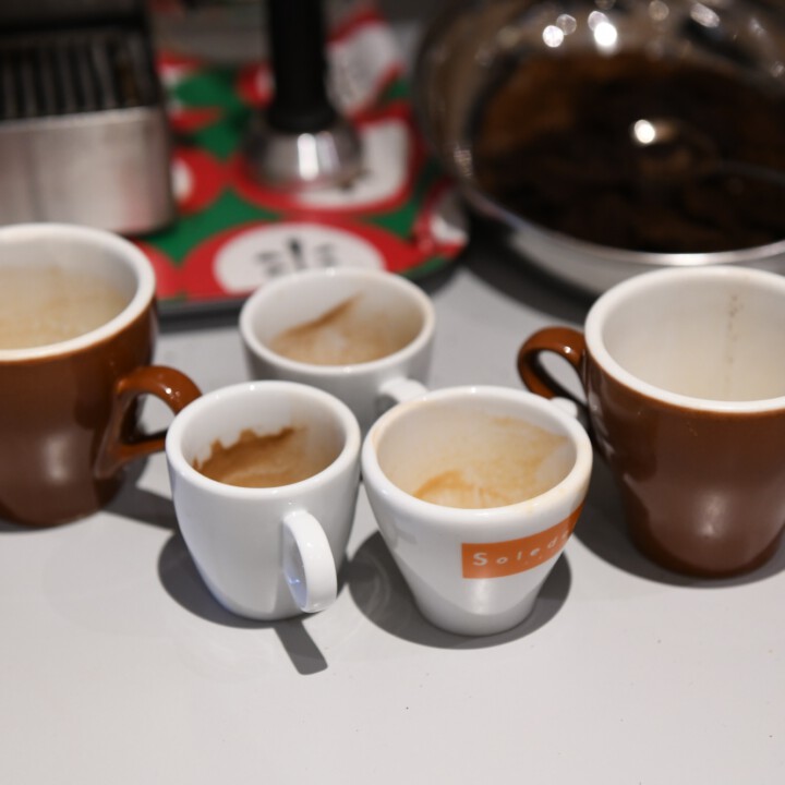 Mehrere leere Espresso‑ und Kaffee-Tassen mit L&ouml;ffeln auf der Theke im Studio‑K&uuml;chenbereich